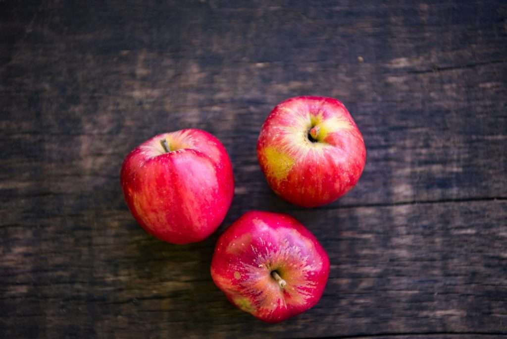 Three red mcintosh apples on wooden table